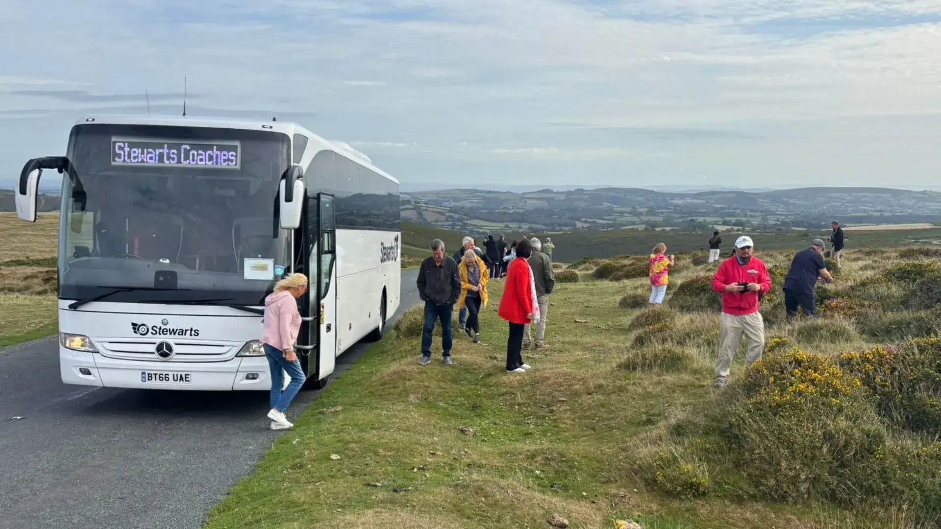 People walking beside coach in hills